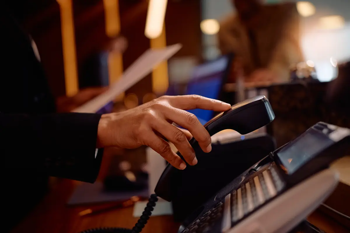 Stock photograph: a hand lifting a telephone receiver from a desk